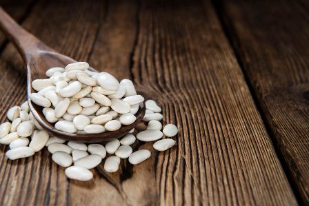 39824596 - portion of white beans (close-up shot) on rustic wooden background